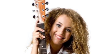 An attractive young teenage woman with an acoustic guitar on white background