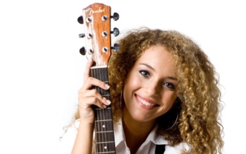 An attractive young teenage woman with an acoustic guitar on white background